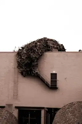 A picture of a house facade with a work of art made of chairs.