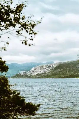 A cloudy picture of the sea in norway with mountains.