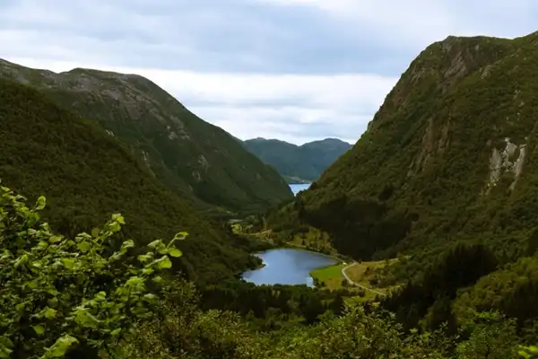 A picture of a vally. Giant mountains left and right. And at the centre of the image, a small lake. Shot from a high view.