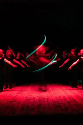 A group of dancers standing around a dancer in the middle spinning.